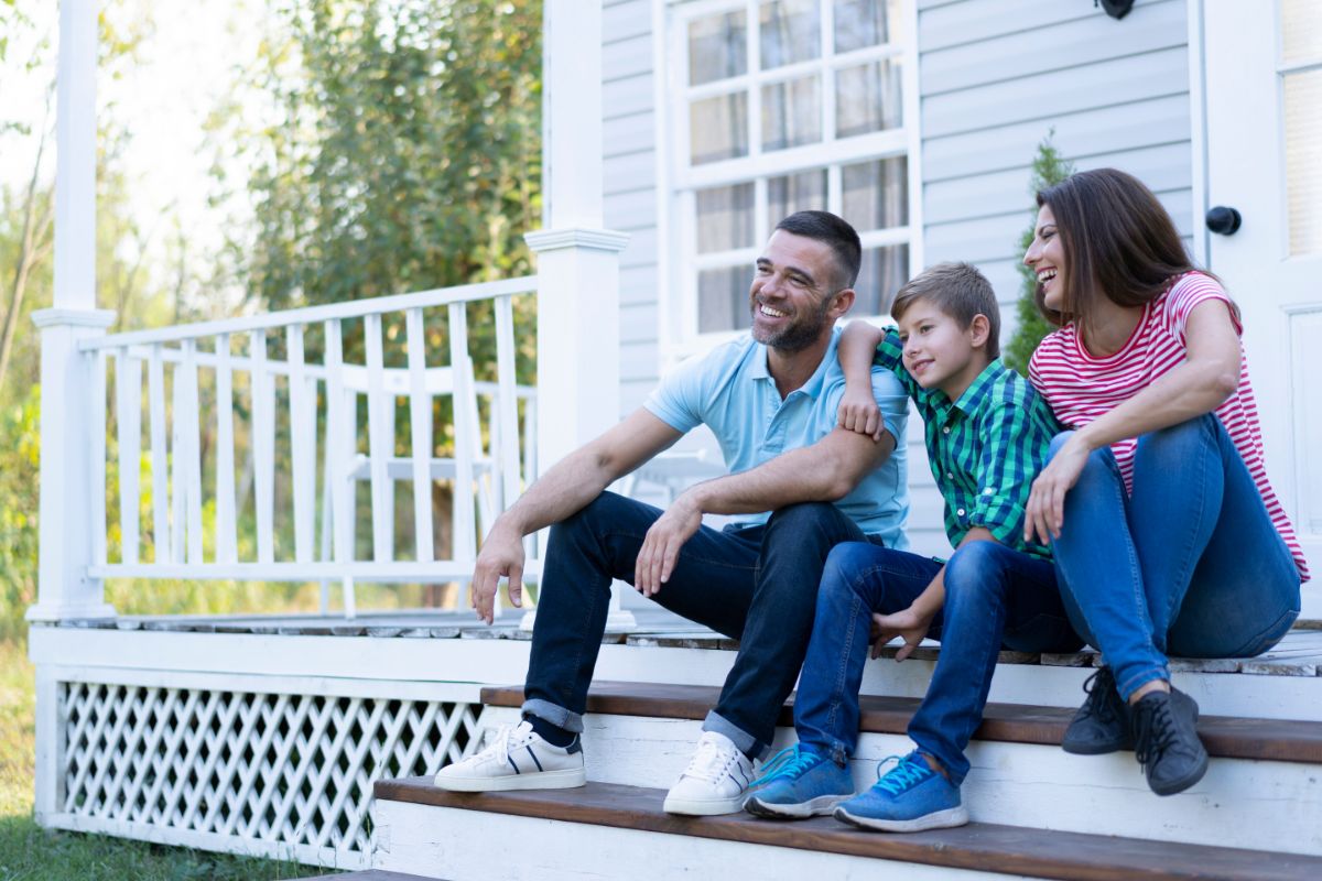 family sitting on front porch of their house