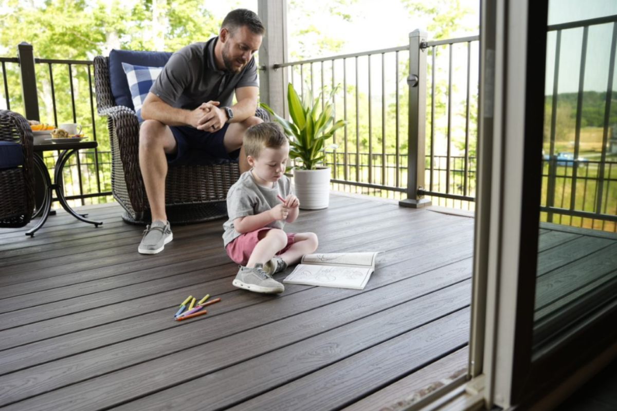 father helping his son on coloring book on the deck of house