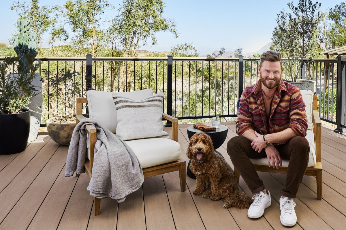 man sitting on the deck of the house with his dog