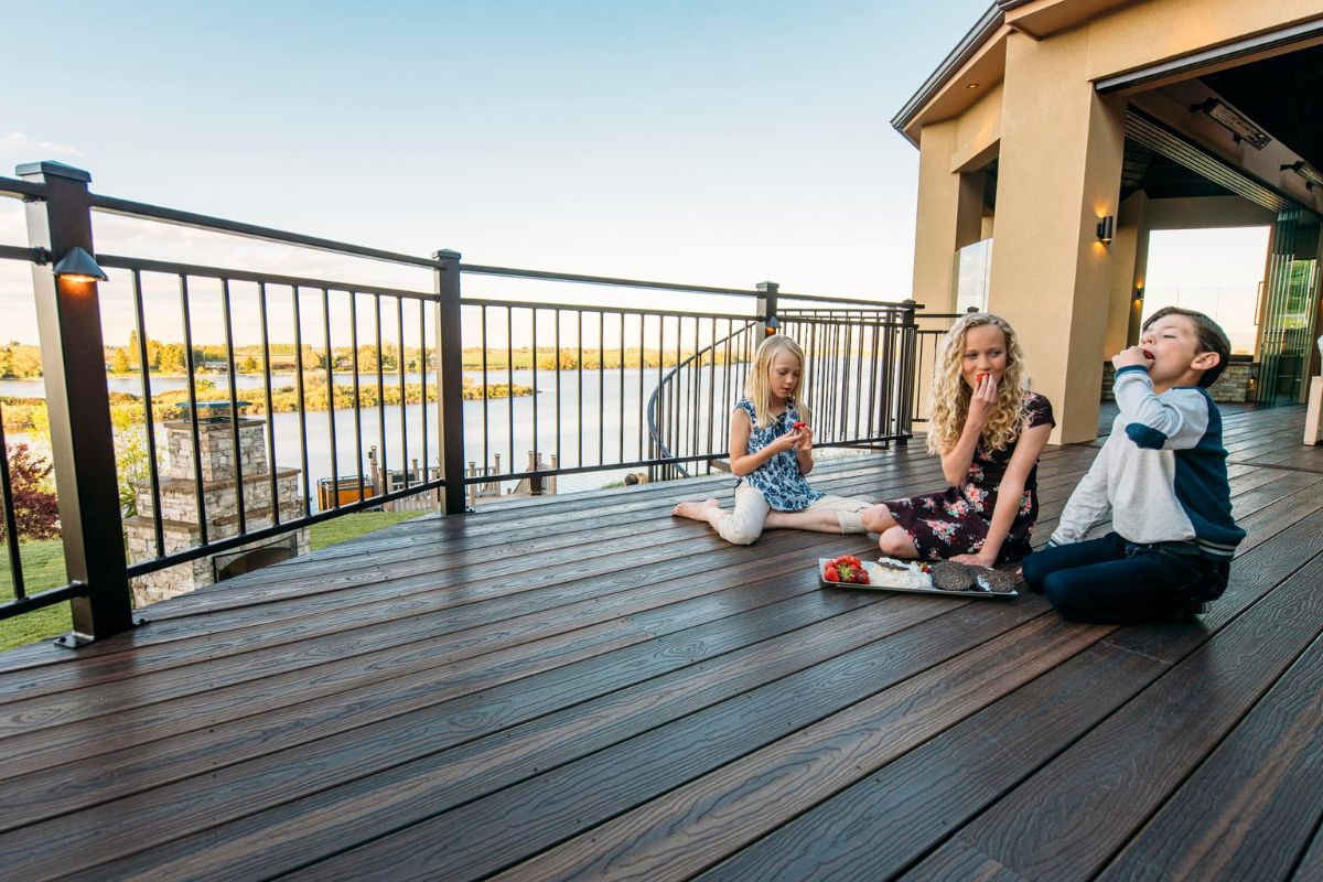 three kids eating together on the deck of house